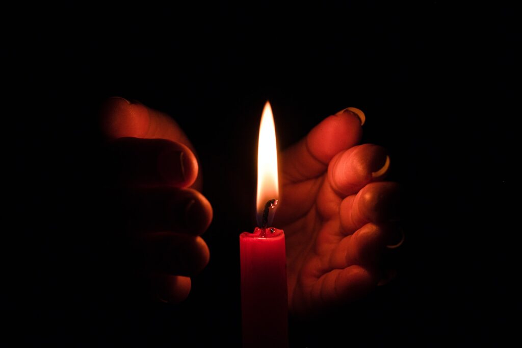Hand protecting candle light from the wind